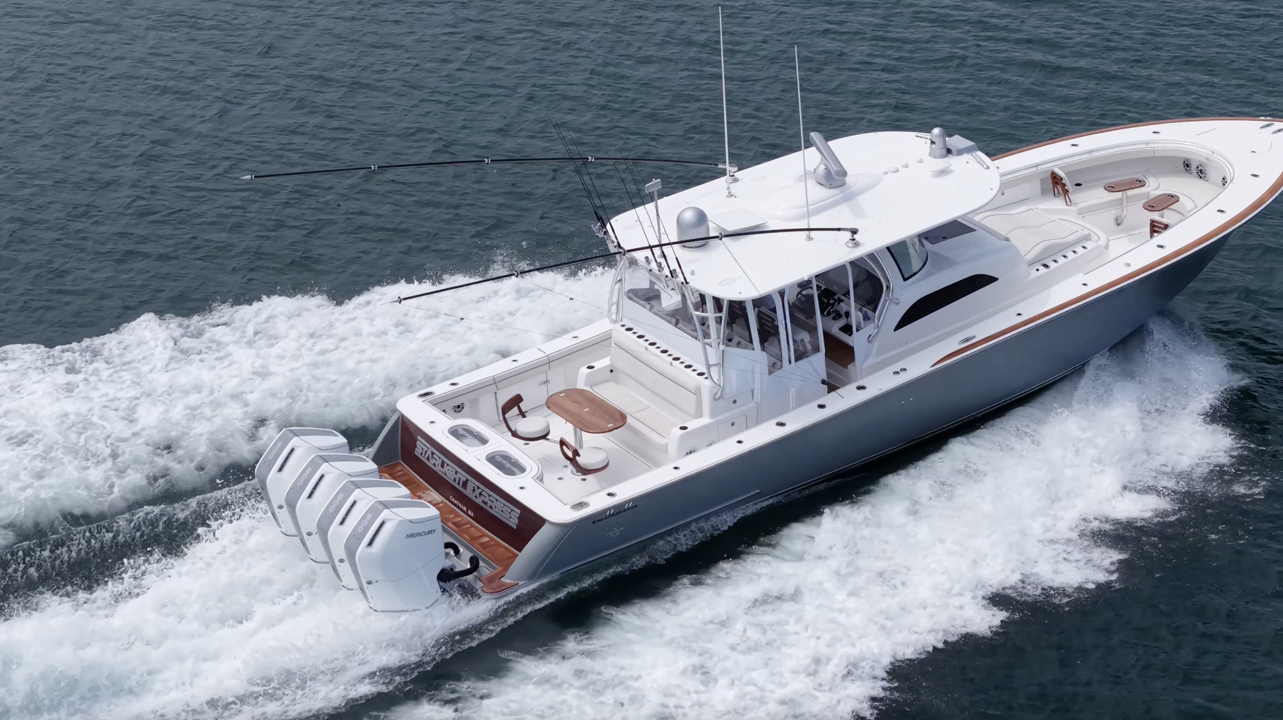 A sleek white motor yacht cruises through the ocean, equipped with four engines and fishing rods, creating a wake in the water.