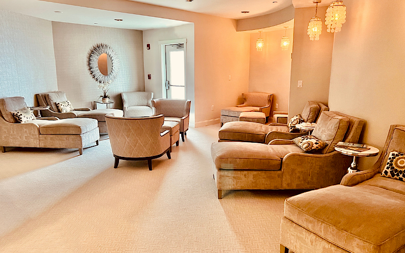 A cozy lounge area with beige seating, decorative pillows, a stylish mirror, and pendant lights, creating a warm and inviting atmosphere.