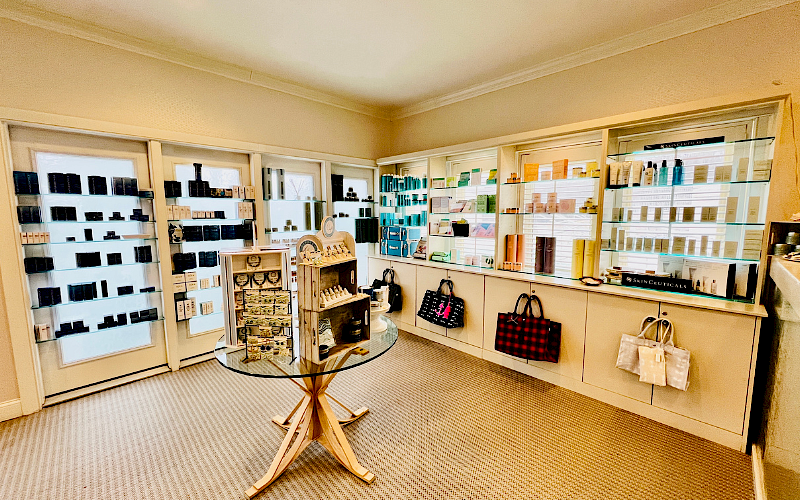 The image shows a well-organized skincare and beauty product display in a store, with shelves of bottles, boxes, and some bags on a table.