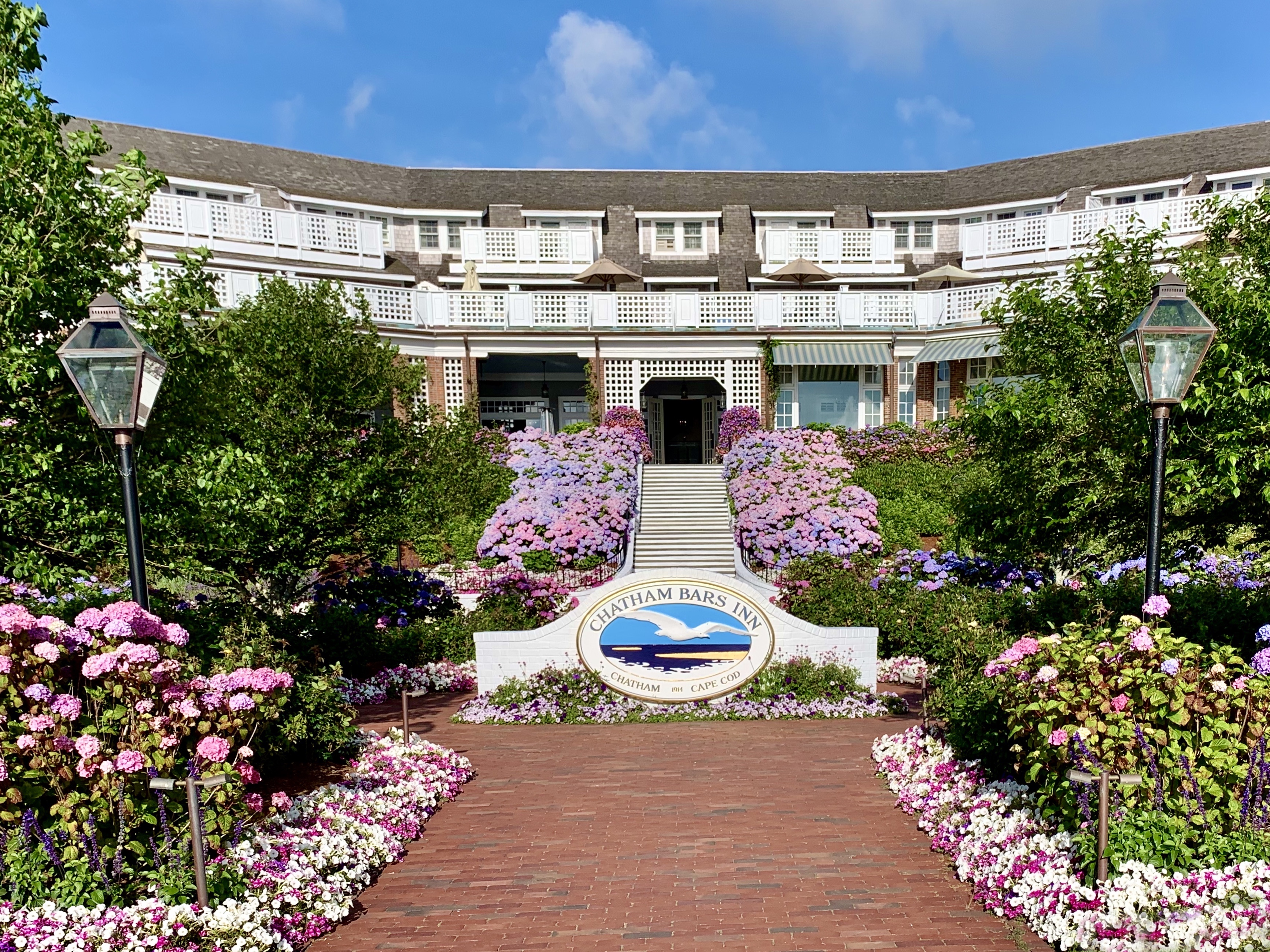 A charming inn with a flower-lined path, colorful gardens, and a welcoming entrance.