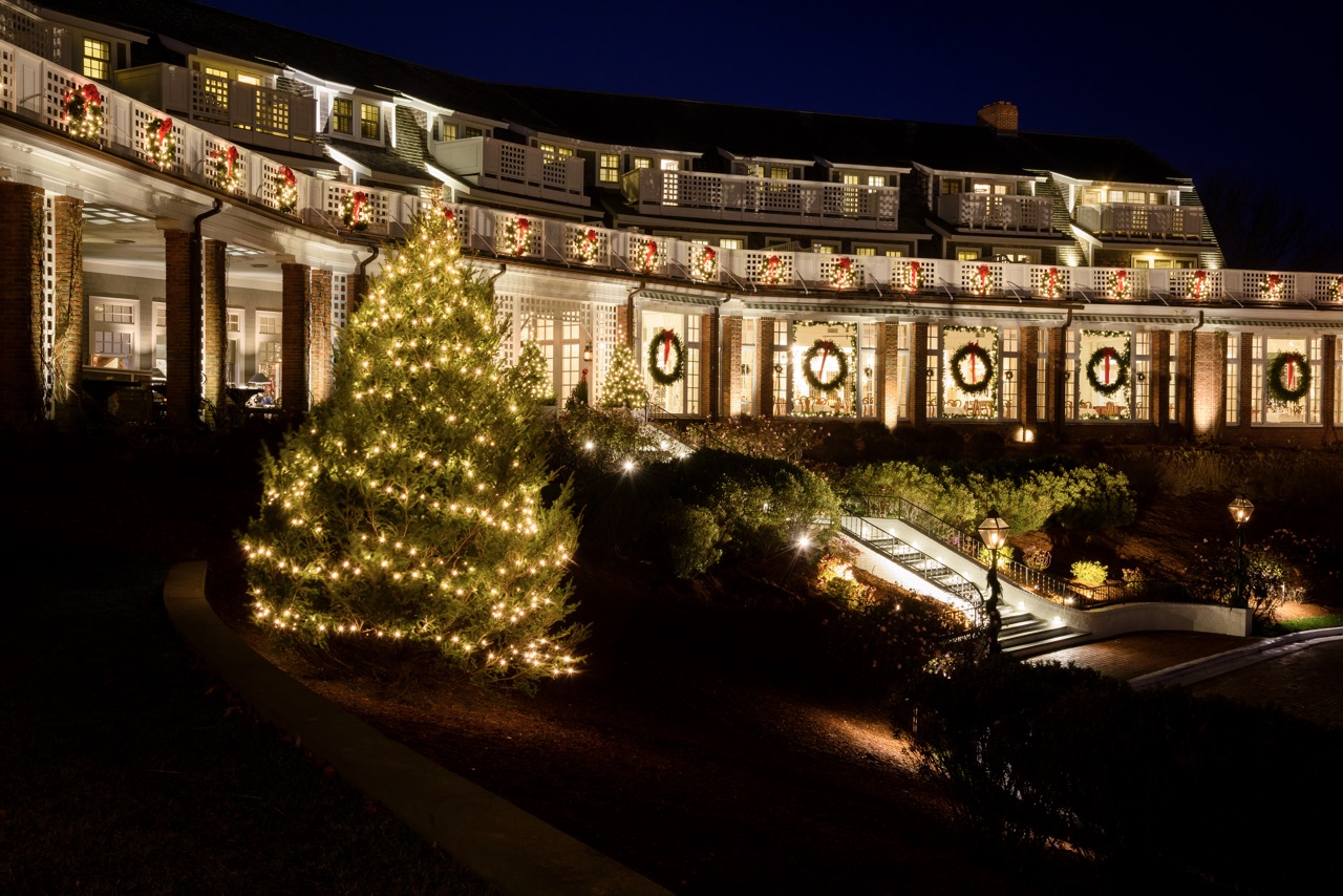 A grand building is adorned with Christmas decorations, lights, and wreaths, creating a festive atmosphere at night.