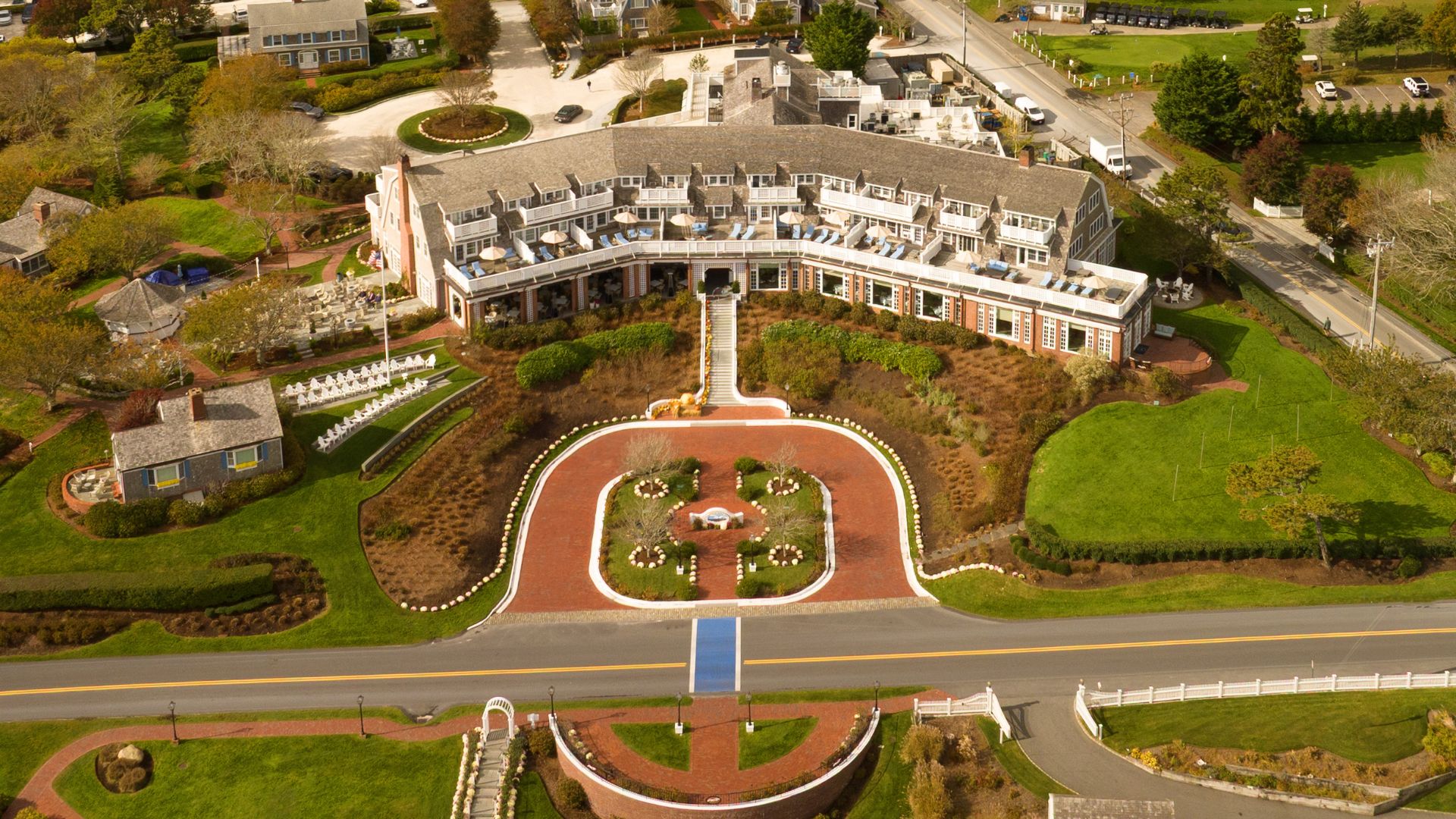The image shows a large building with a garden and surrounding landscape, along with residential buildings and roads.
