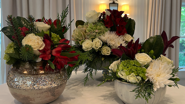 The image shows three floral arrangements featuring white roses, red lilies, green hydrangeas, and various greenery in decorative vases.