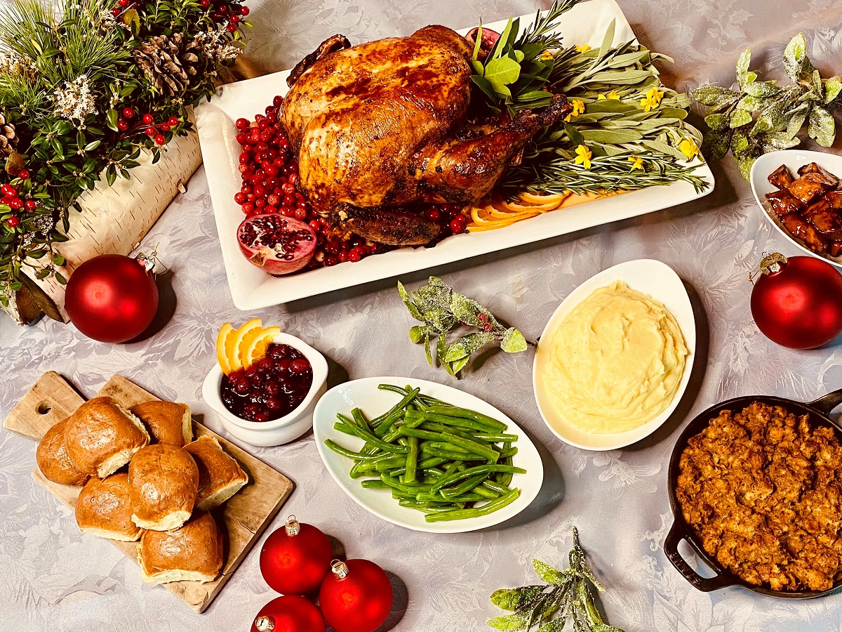 A festive table with roast turkey, sides like mashed potatoes and green beans, rolls, and holiday decorations, creating a holiday feast.