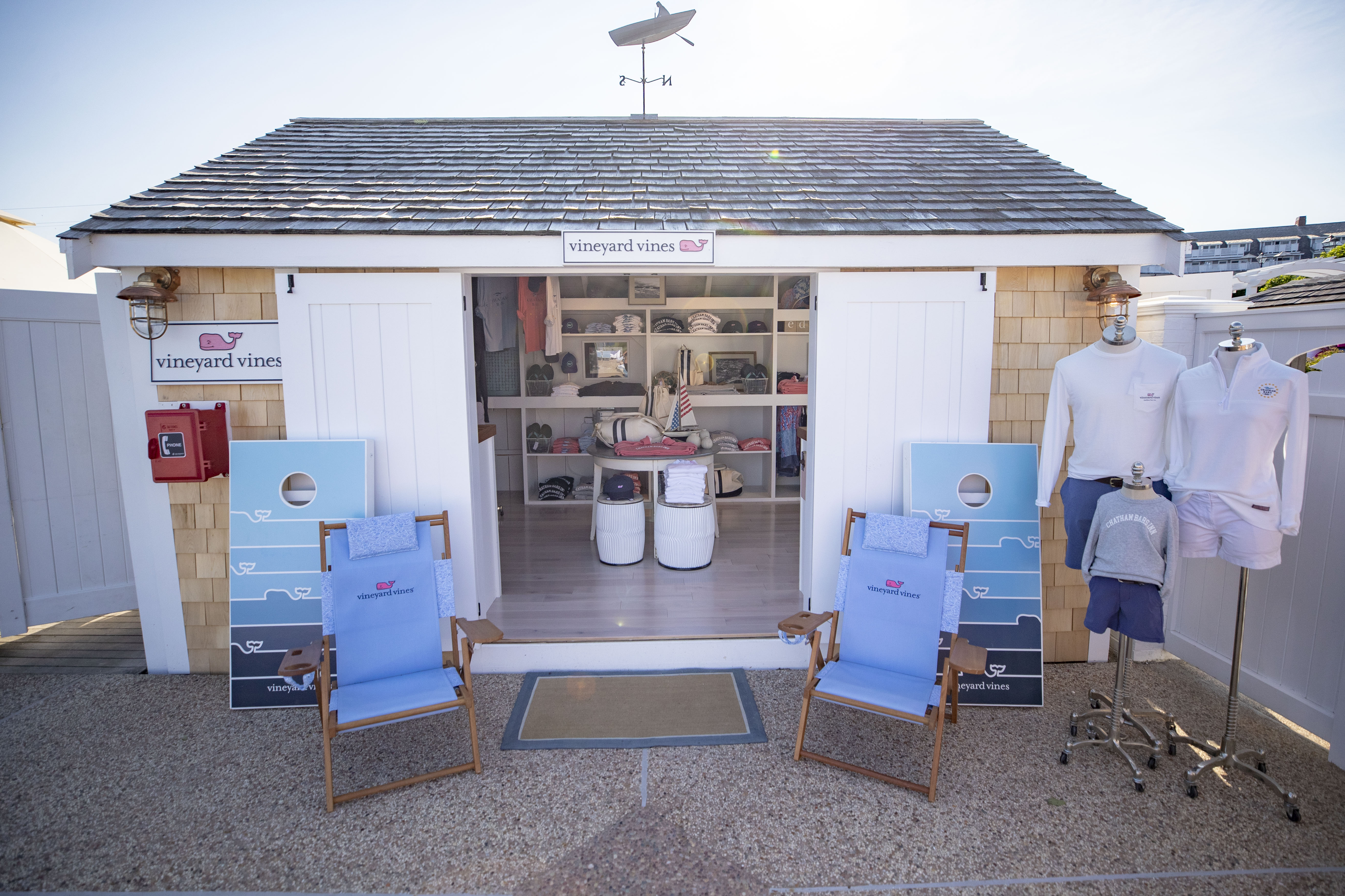 A small retail shop with "Vineyard Vines" branding, showcasing beach chairs, mannequins, and clothing inside.
