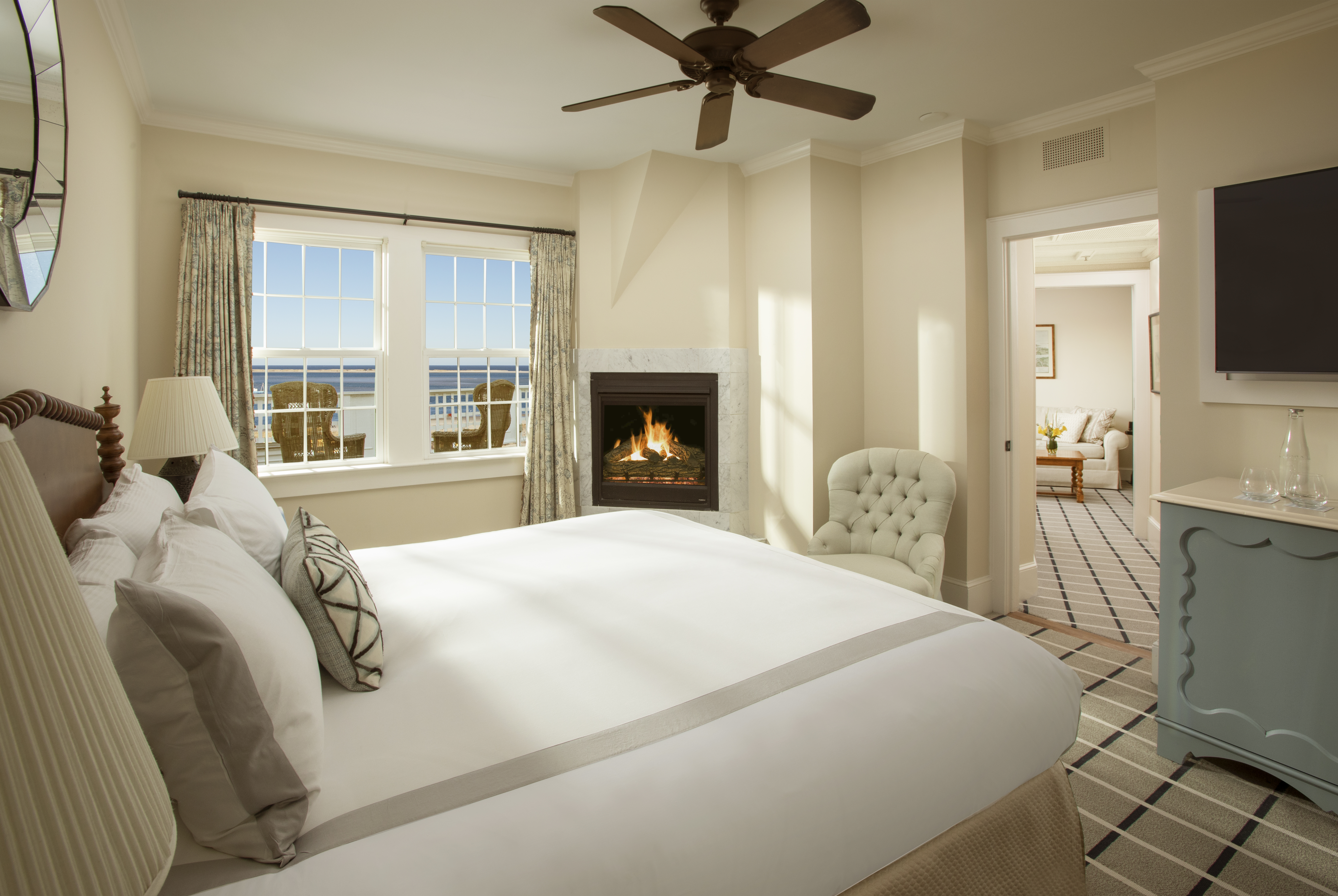 Coastal homes overlook a scenic bay with boats and sandy beaches, surrounded by green landscapes and clear blue water.