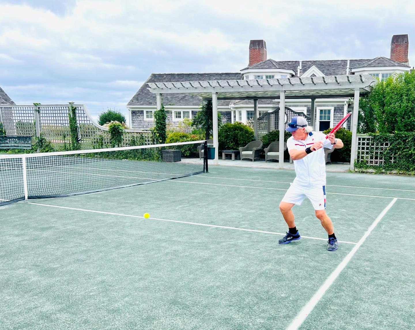Tennis Pro showing a backhand shot on a har tru court