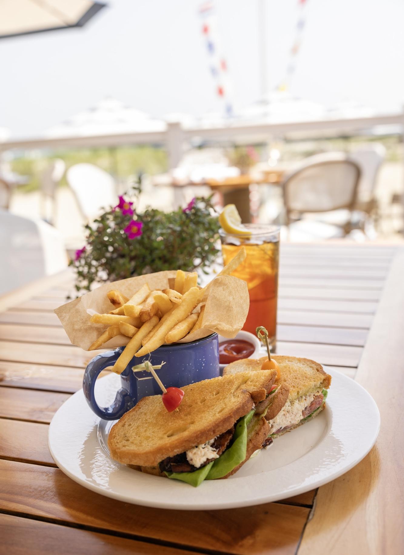 Crab BLT on white plate, fries on wooden table