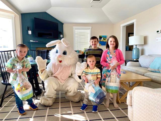Easter Bunny with four smiling children holding baskets indoors.