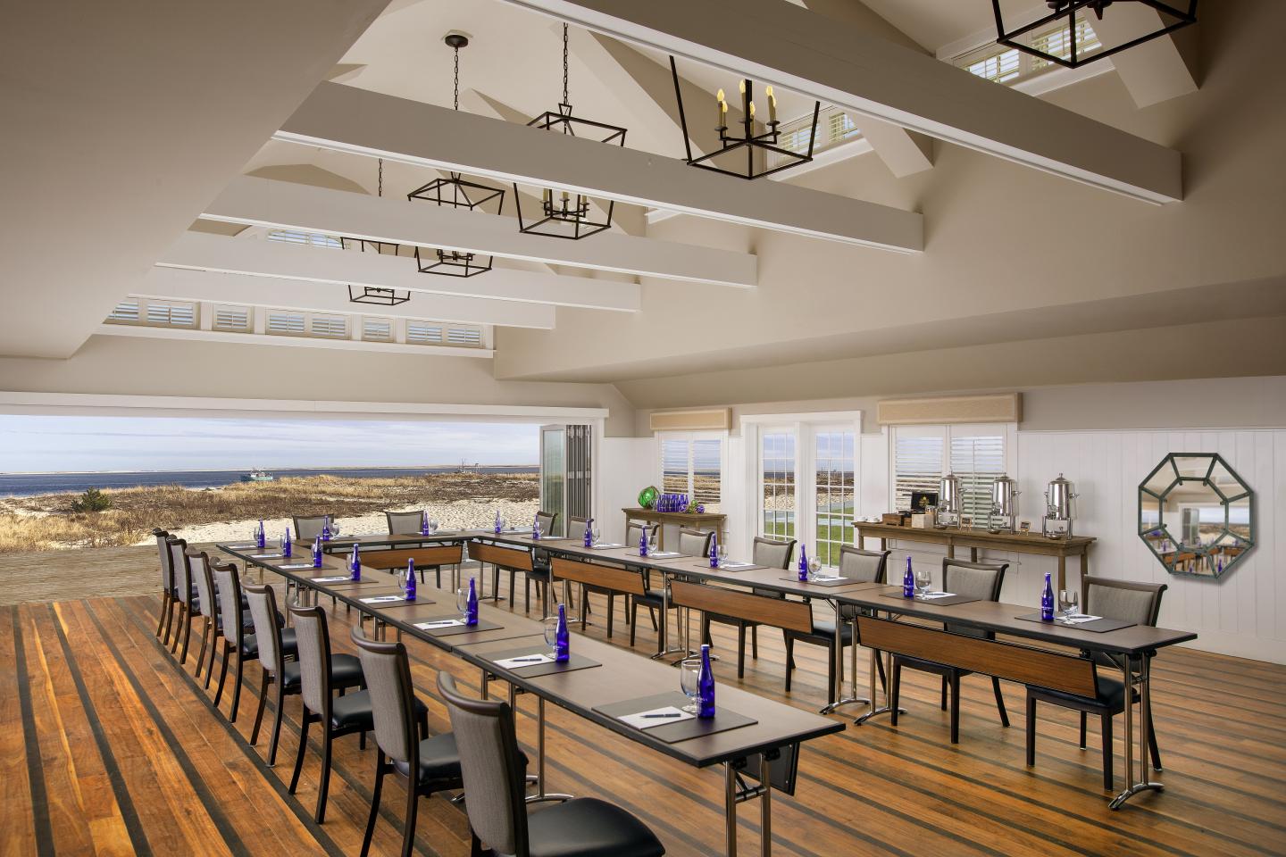 Spacious, elegantly set conference room with ocean view and wooden floor.
