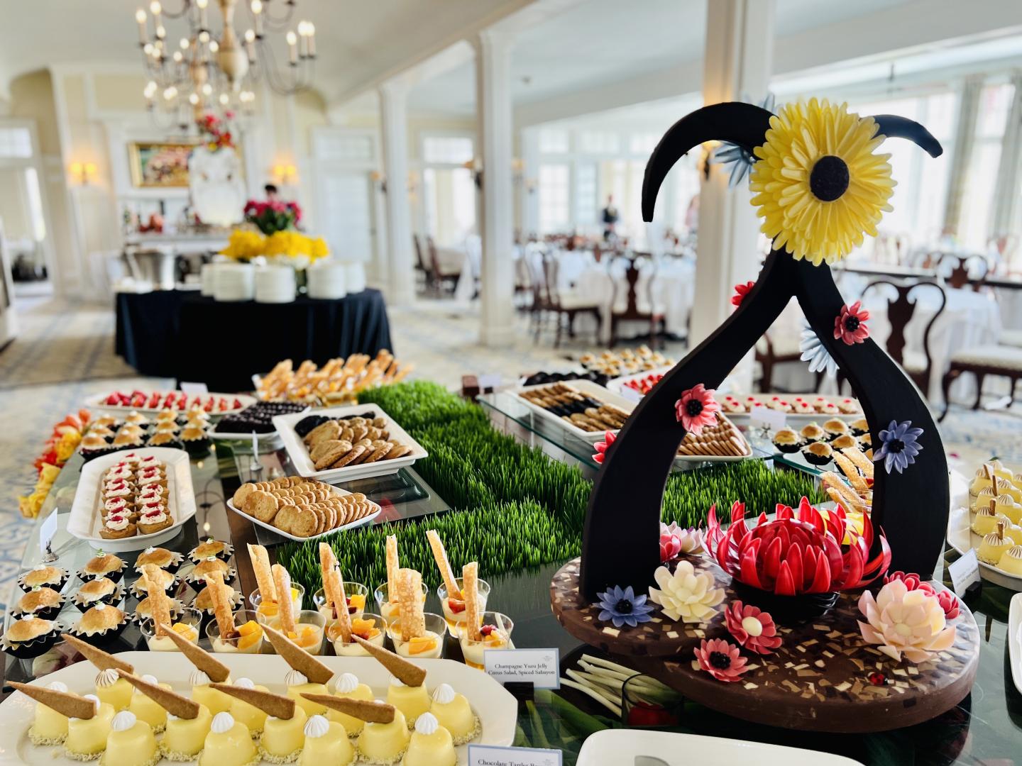 Elegant buffet with assorted desserts and a floral centerpiece in a bright dining room.