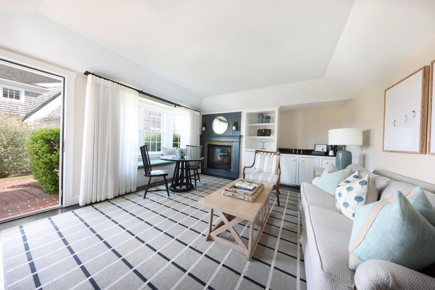 Bright living room with striped rug, couch, fireplace, and large window.