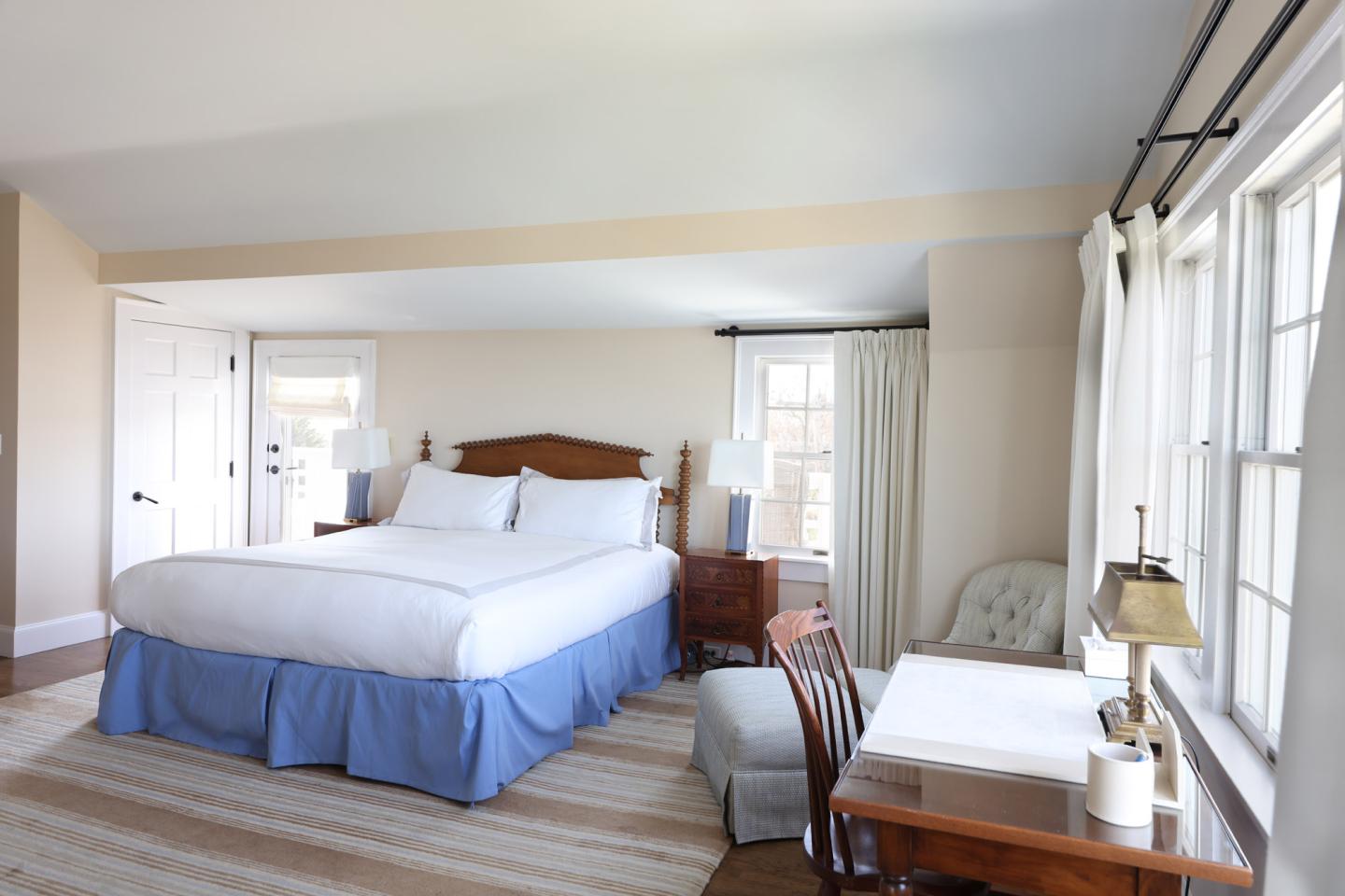 Spacious bedroom with a large bed, wooden desk, and natural light from a window.
