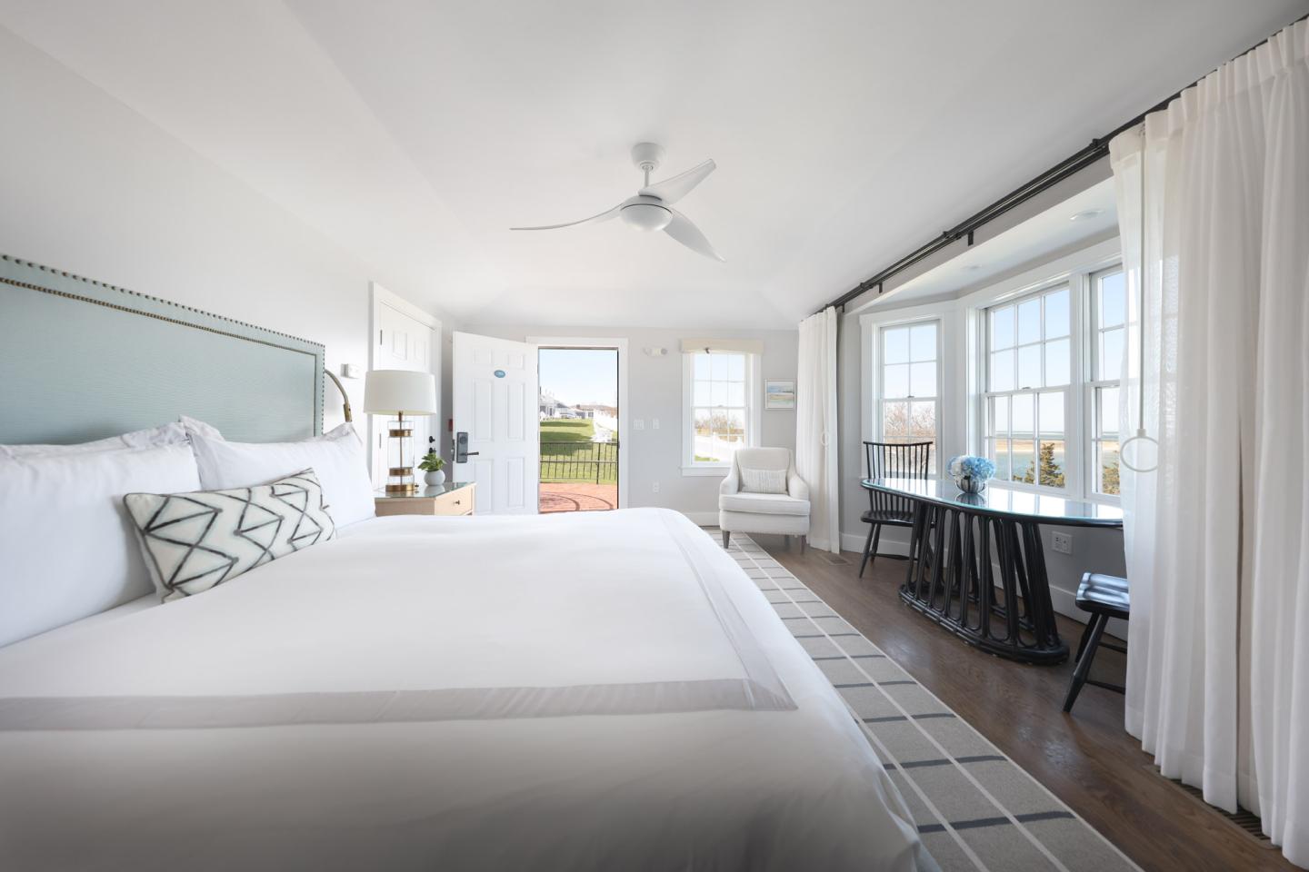 Bright, modern bedroom with a large bed, ceiling fan, and bay window.
