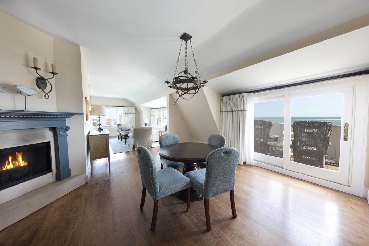 Spacious living room with fireplace, round table, and ocean view through large windows.