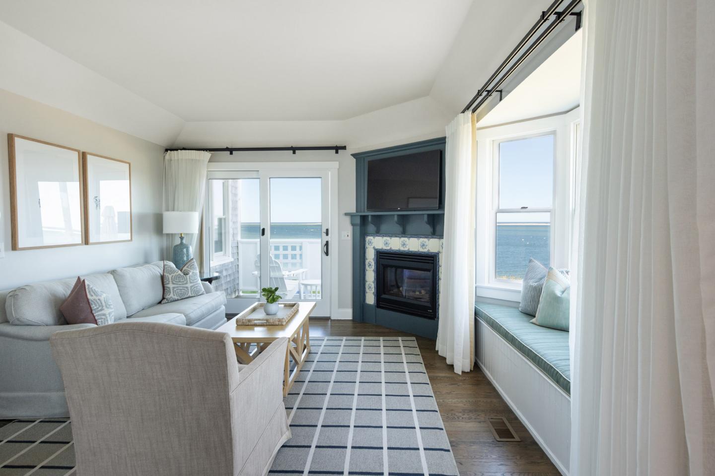 Chic living room with ocean view, beige sofa, fireplace, and large windows.