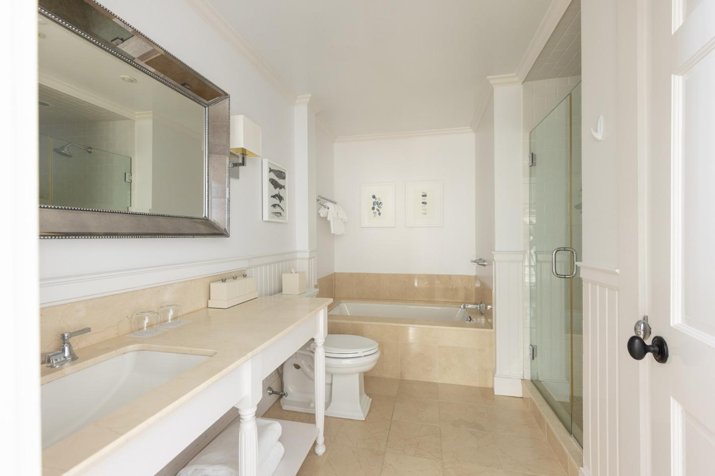 Modern white bathroom with glass shower, bathtub, and large mirror.