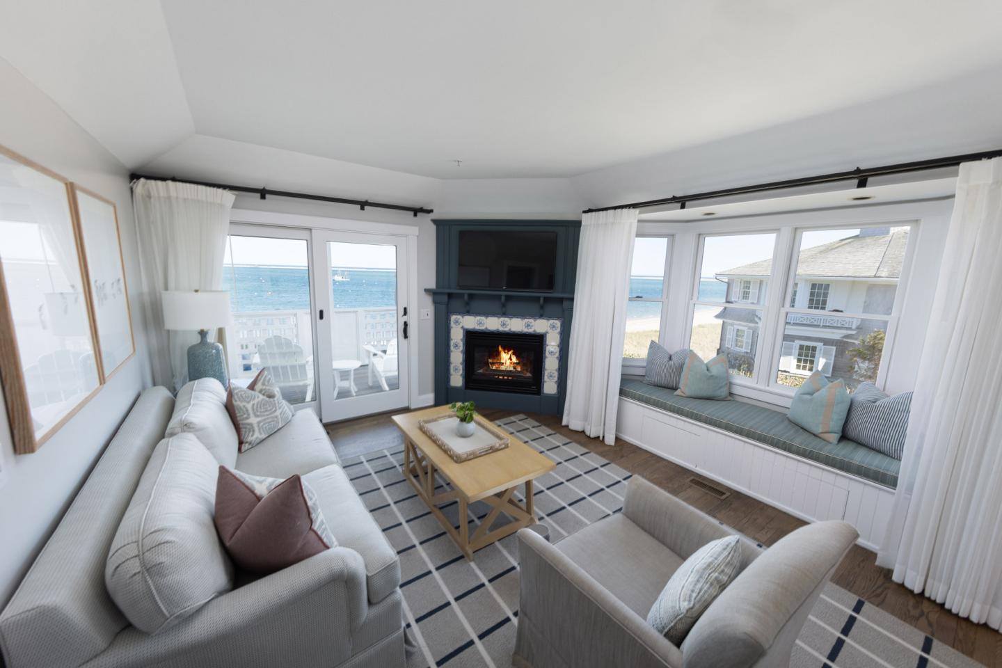 Cozy living room with ocean view, fireplace, and soft gray furniture.