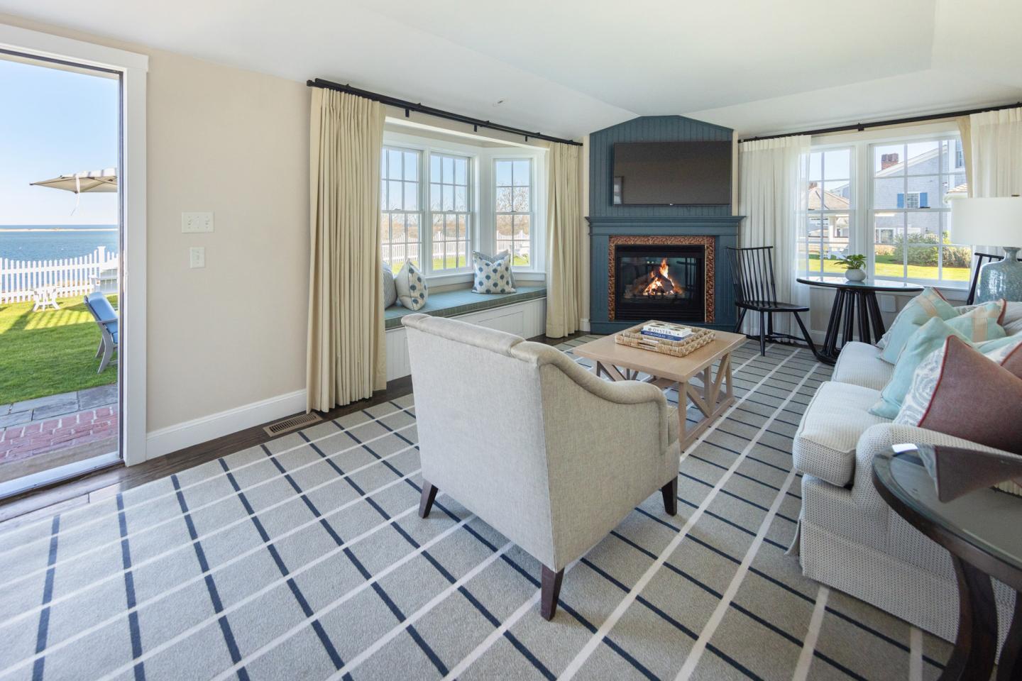 Cozy living room with fireplace, sofa, and sea view through large windows.