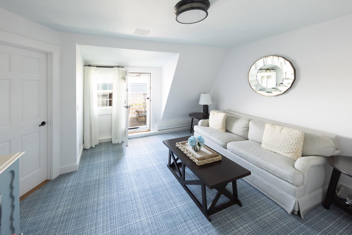 Bright living room with a gray sofa, coffee table, and round mirror on the wall.
