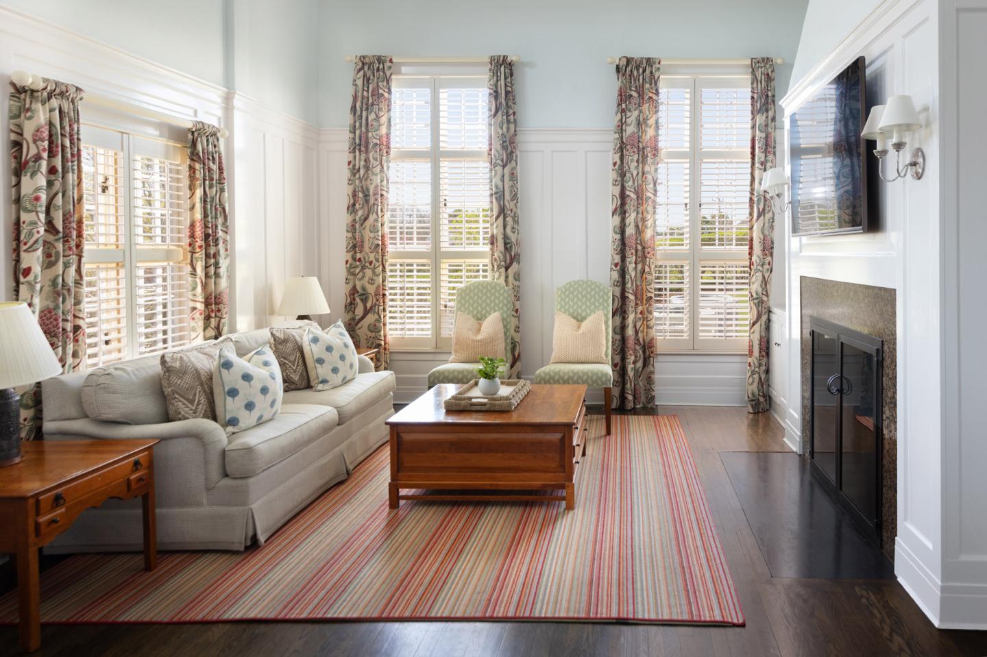 Bright living room with striped rug, sofa, patterned curtains, and fireplace.
