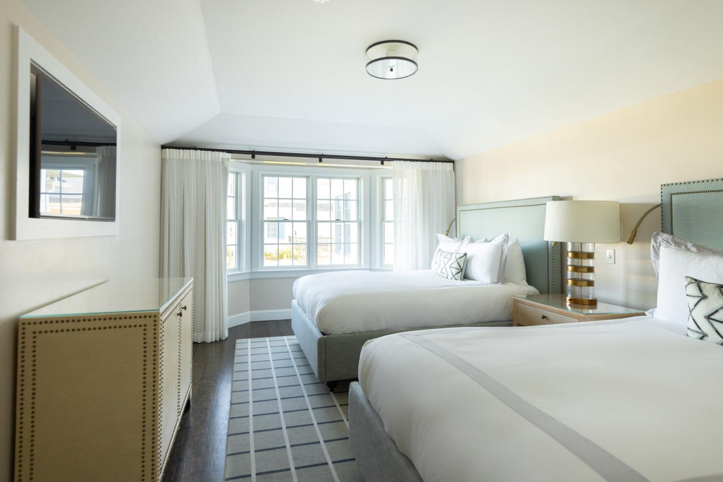 Cozy hotel room with two beds, large window, and neutral tones.