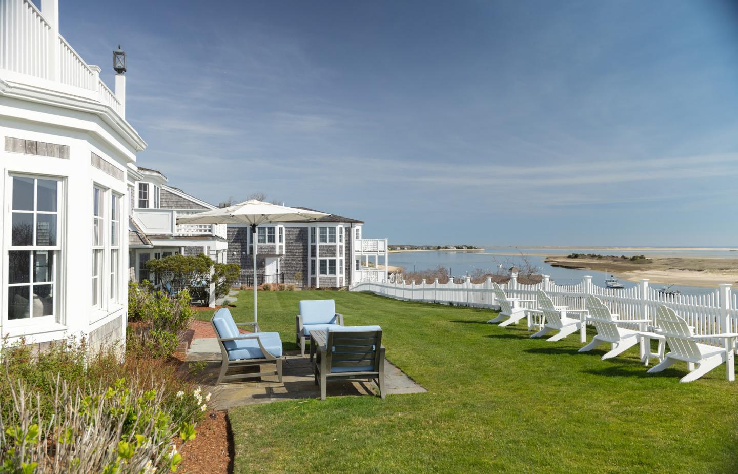 Coastal hotel lawn with white chairs and ocean view.