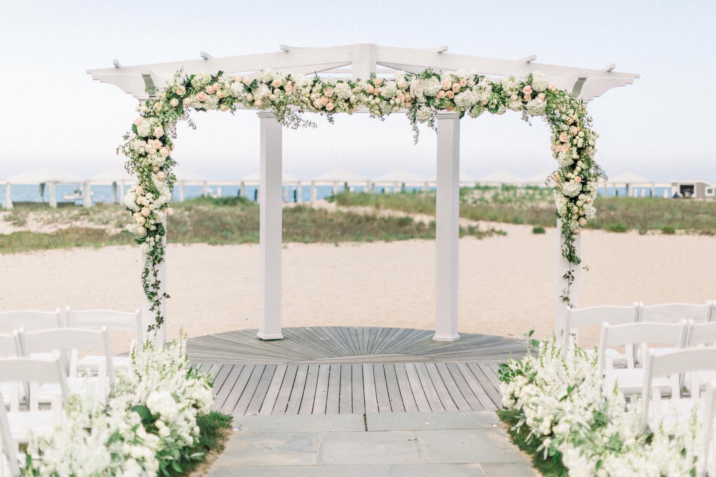 Wedding arch with flowers on a sandy beach setting.