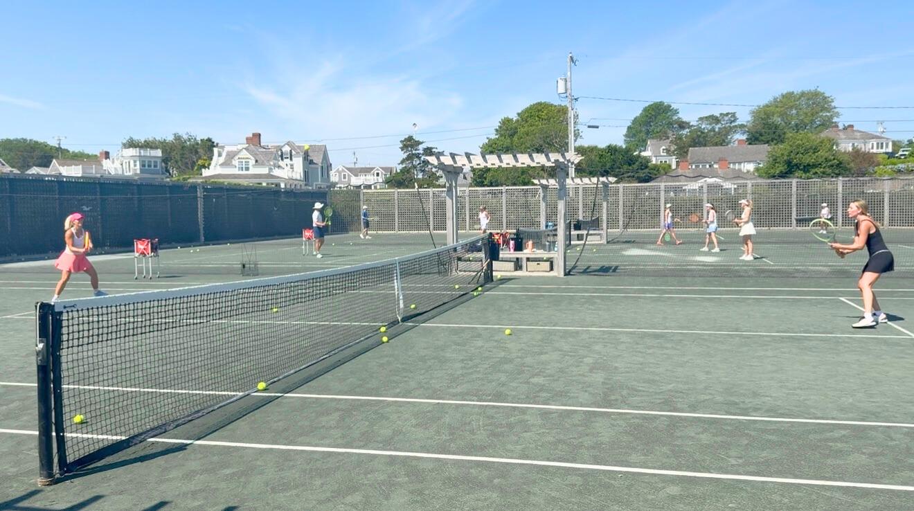 Tennis players practicing on a sunny outdoor court.