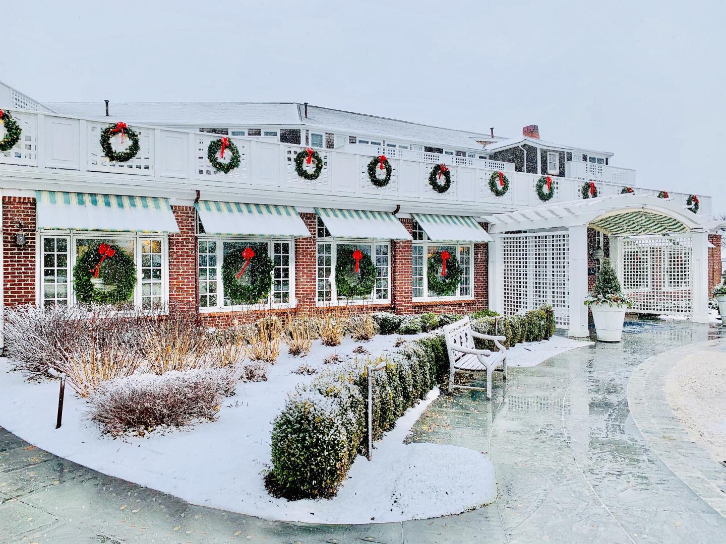 Snow-covered building decorated with holiday wreaths and striped awnings.