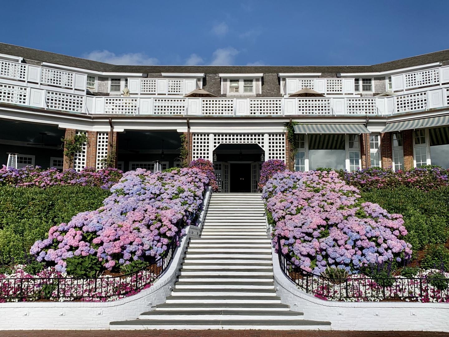 Grand white building with flower-lined steps under a clear blue sky.