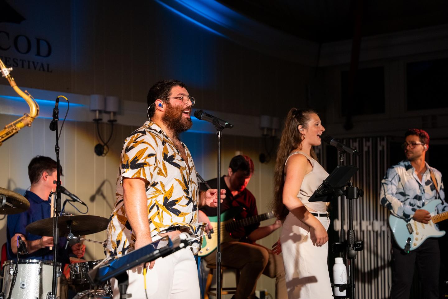 Band performing on stage with colorful lighting and musical instruments.