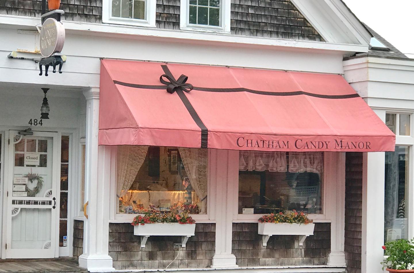 Red storefront awning with decorative windows and flower boxes.