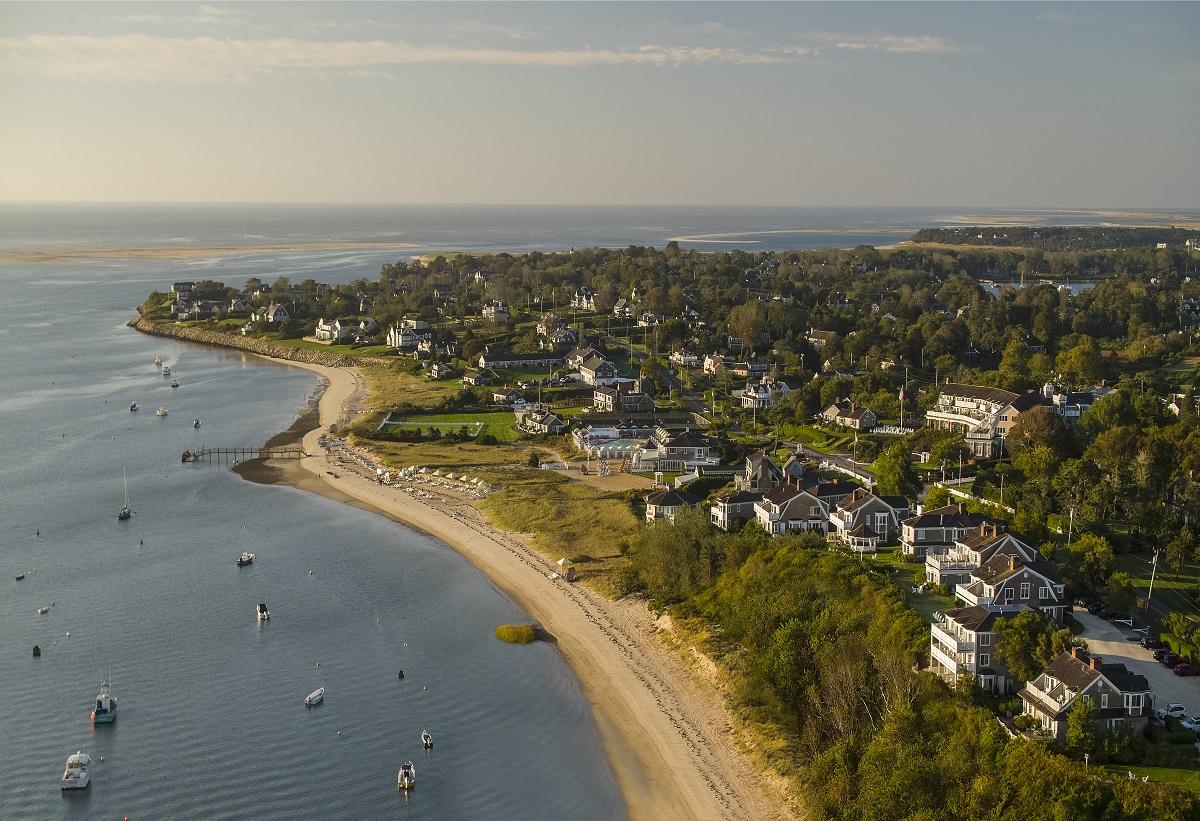 Coastal town with sandy beaches, houses, and boats on a sunny day.
