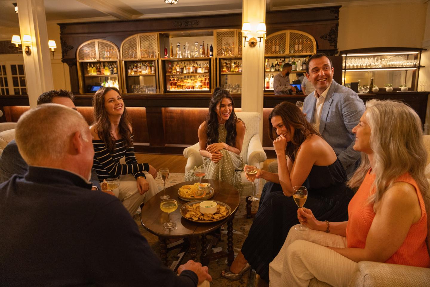 Group of people laughing and chatting in a cozy bar setting.