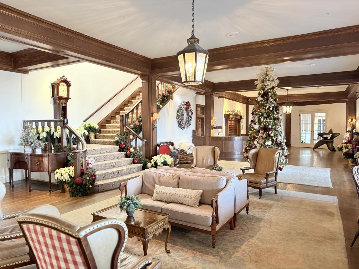 Elegant living room with Christmas tree, wooden beams, and plush seating.