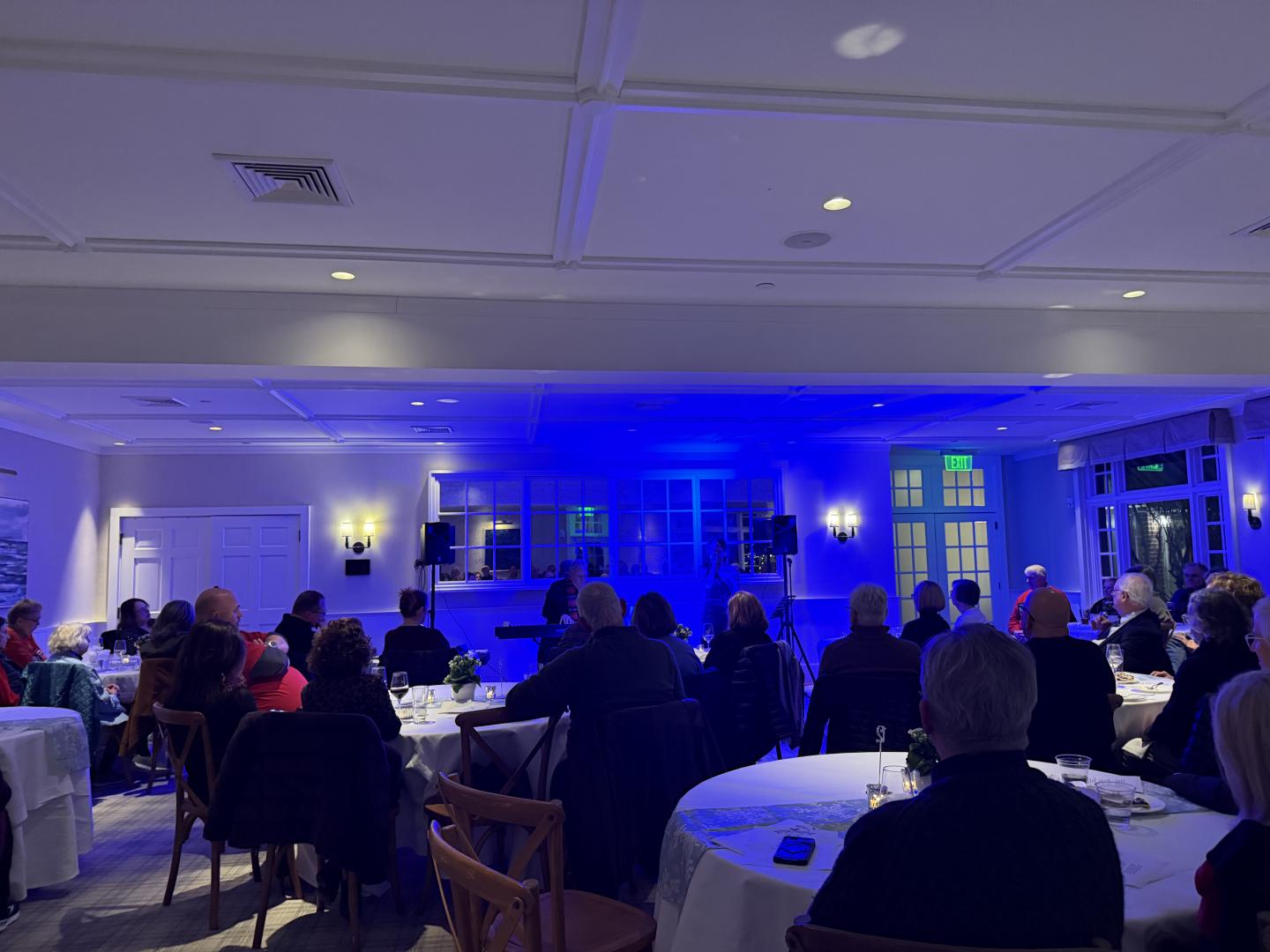 Audience seated in a dimly lit room with blue lighting.