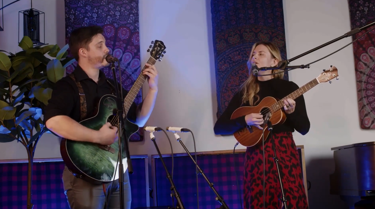 Musicians playing guitars in a studio with microphones.