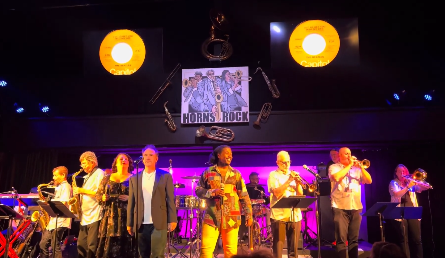 Musicians performing on stage with vibrant lighting and instruments.