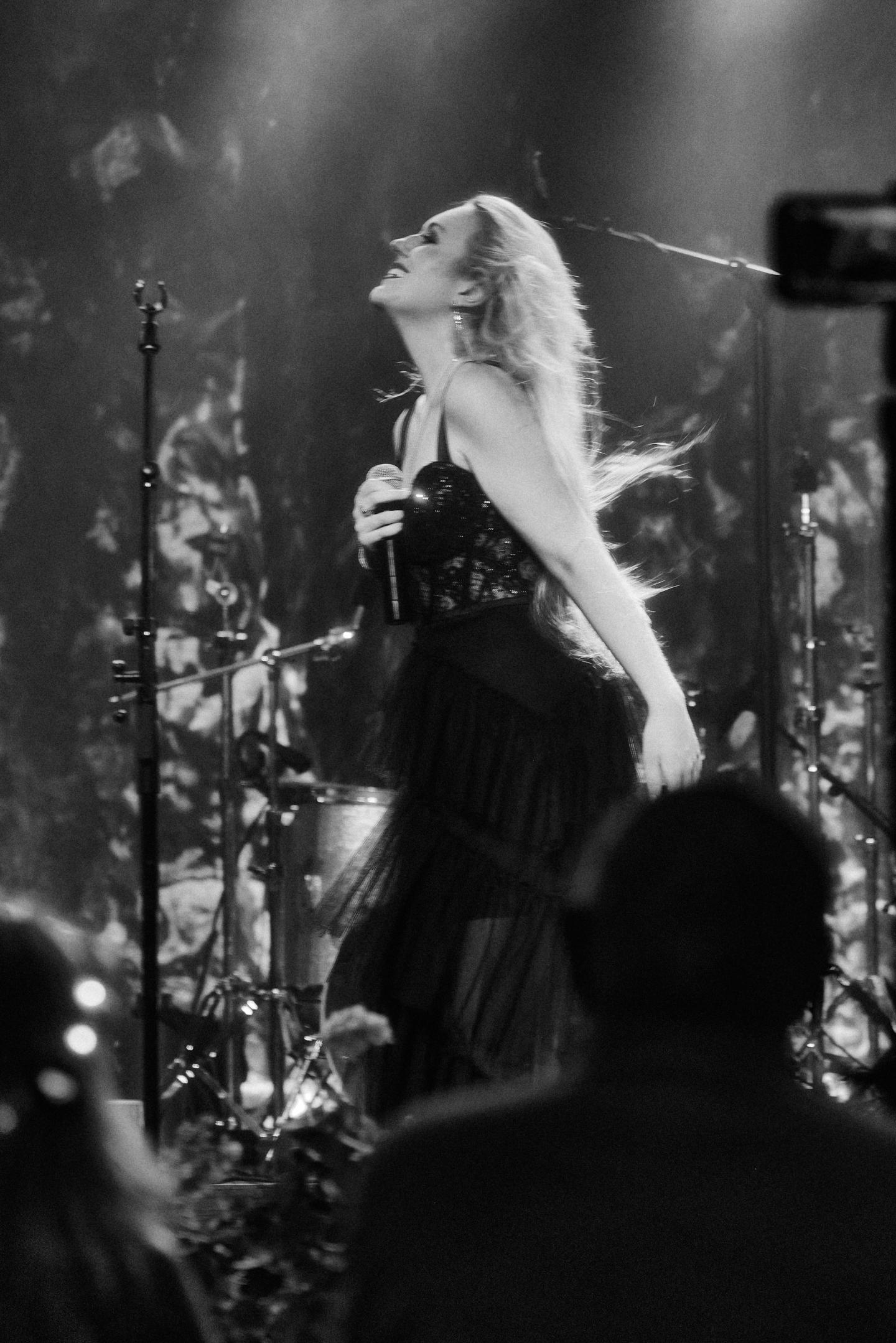 Singer performing passionately on stage in black and white.