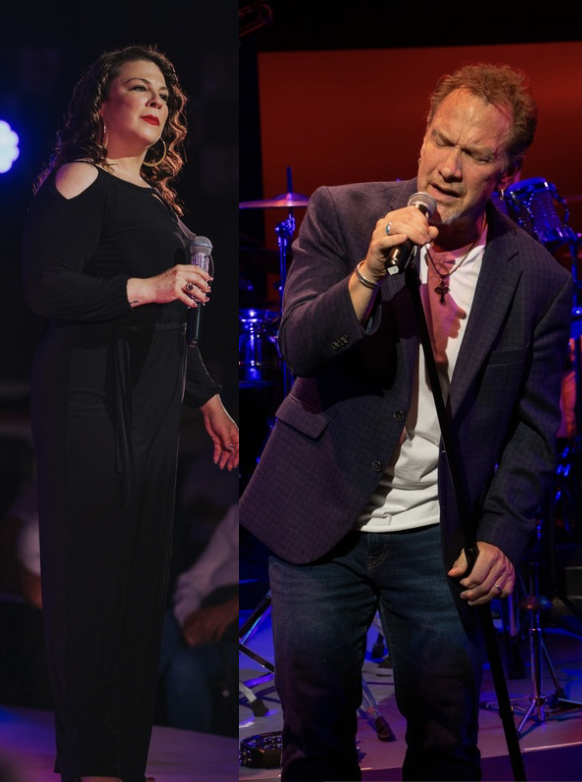 Singer performing on stage, microphone in hand, with band in the background.