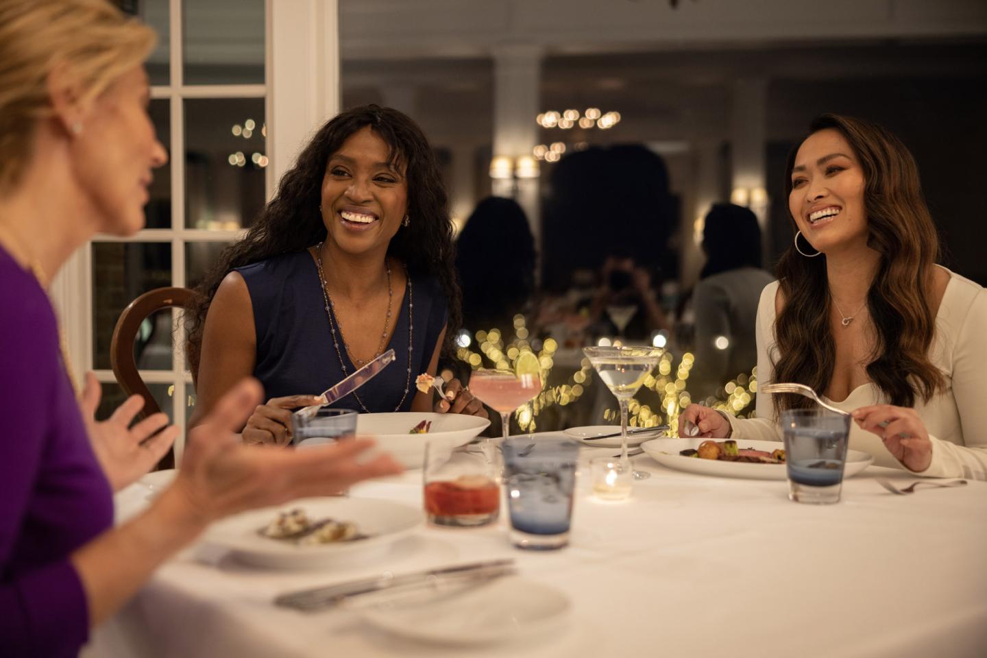 Women laughing and dining at a restaurant table.