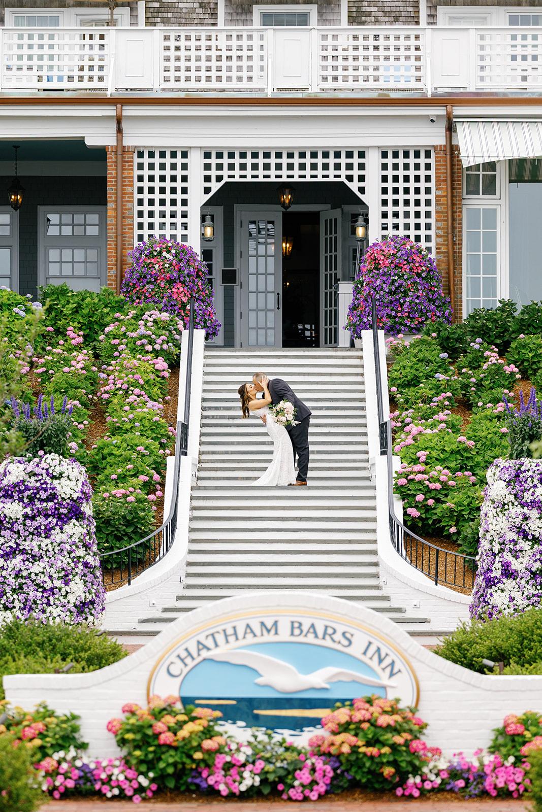 Couple kissing on stairs surrounded by colorful flowers at Chatham Bars Inn.