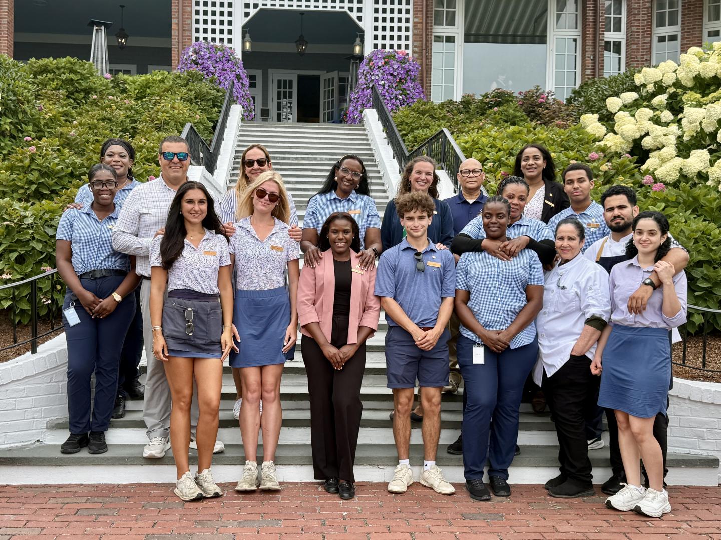 Group of people in uniform posing on steps outside a building.