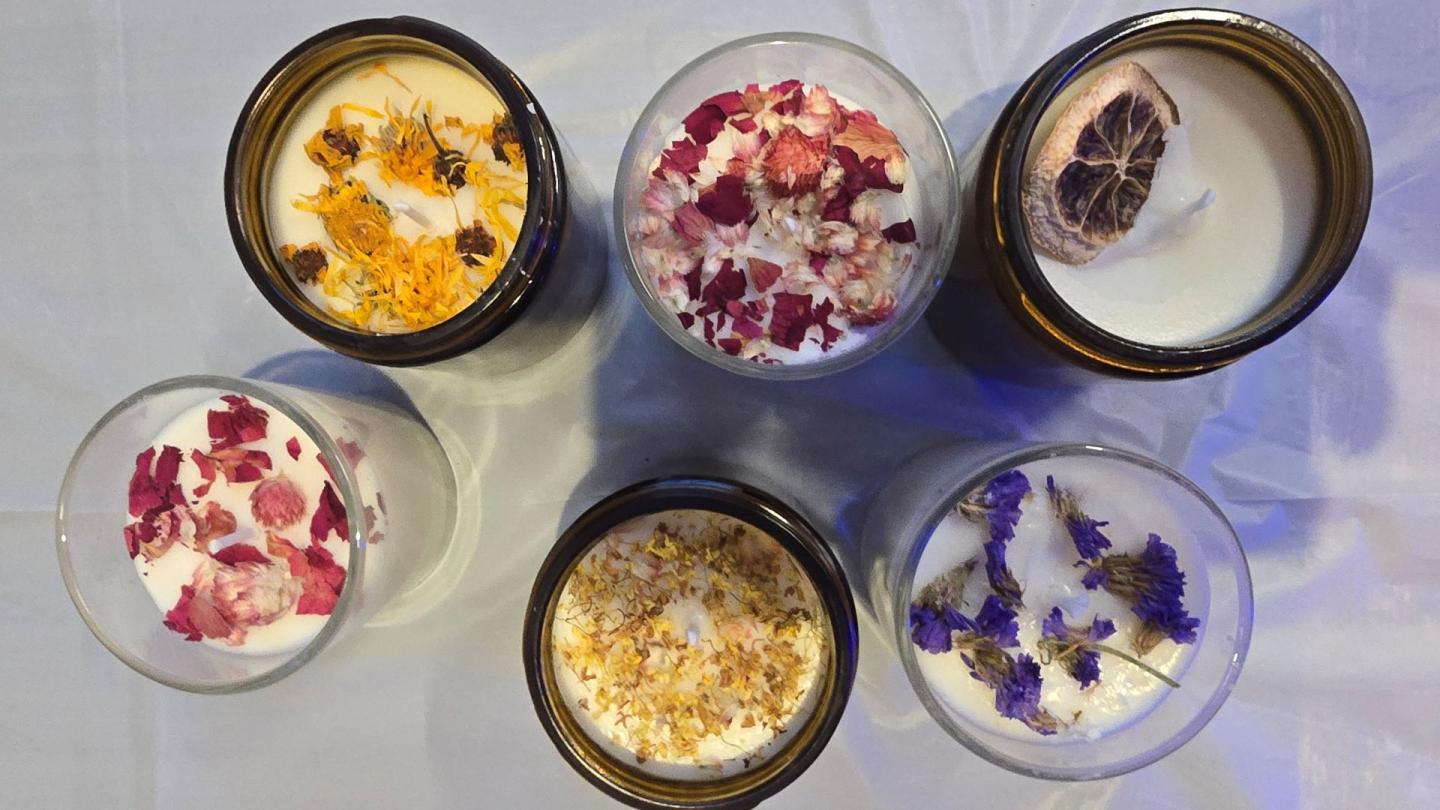 Six decorated candles with dried flowers and fruit slices.