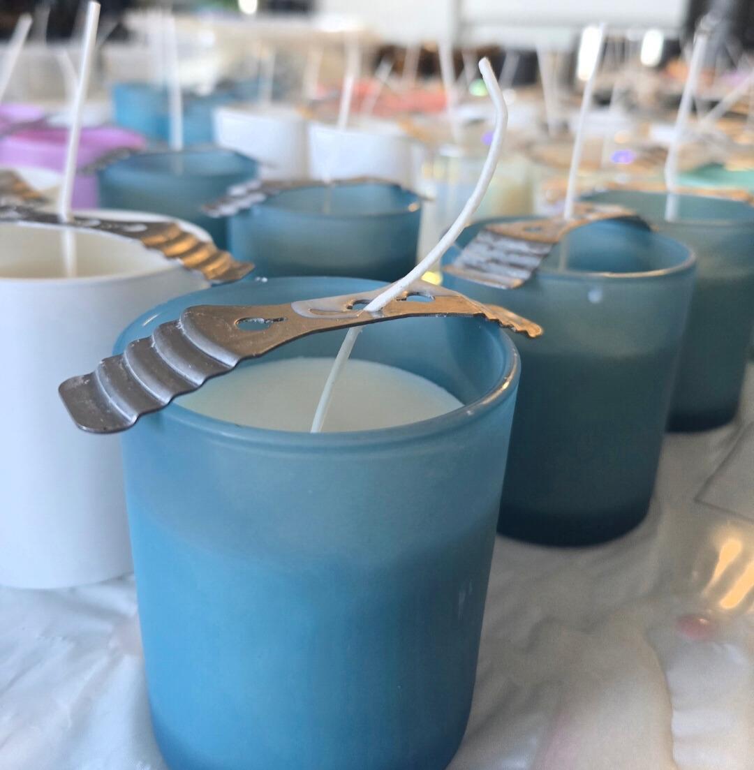 Blue and white candles with wicks supported by metal clips.