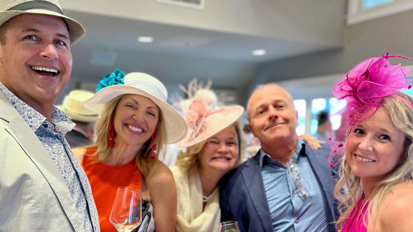 Group smiling in colorful hats at a festive event indoors.