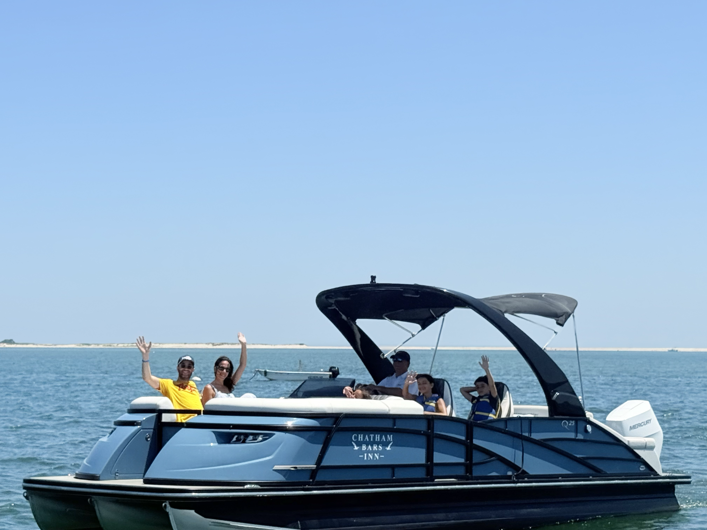 Boat on water with smiling people under a clear blue sky.