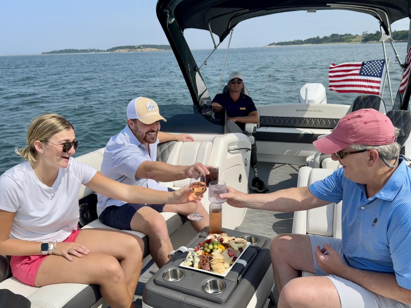 Four people on a boat enjoying drinks and snacks under sunny skies.