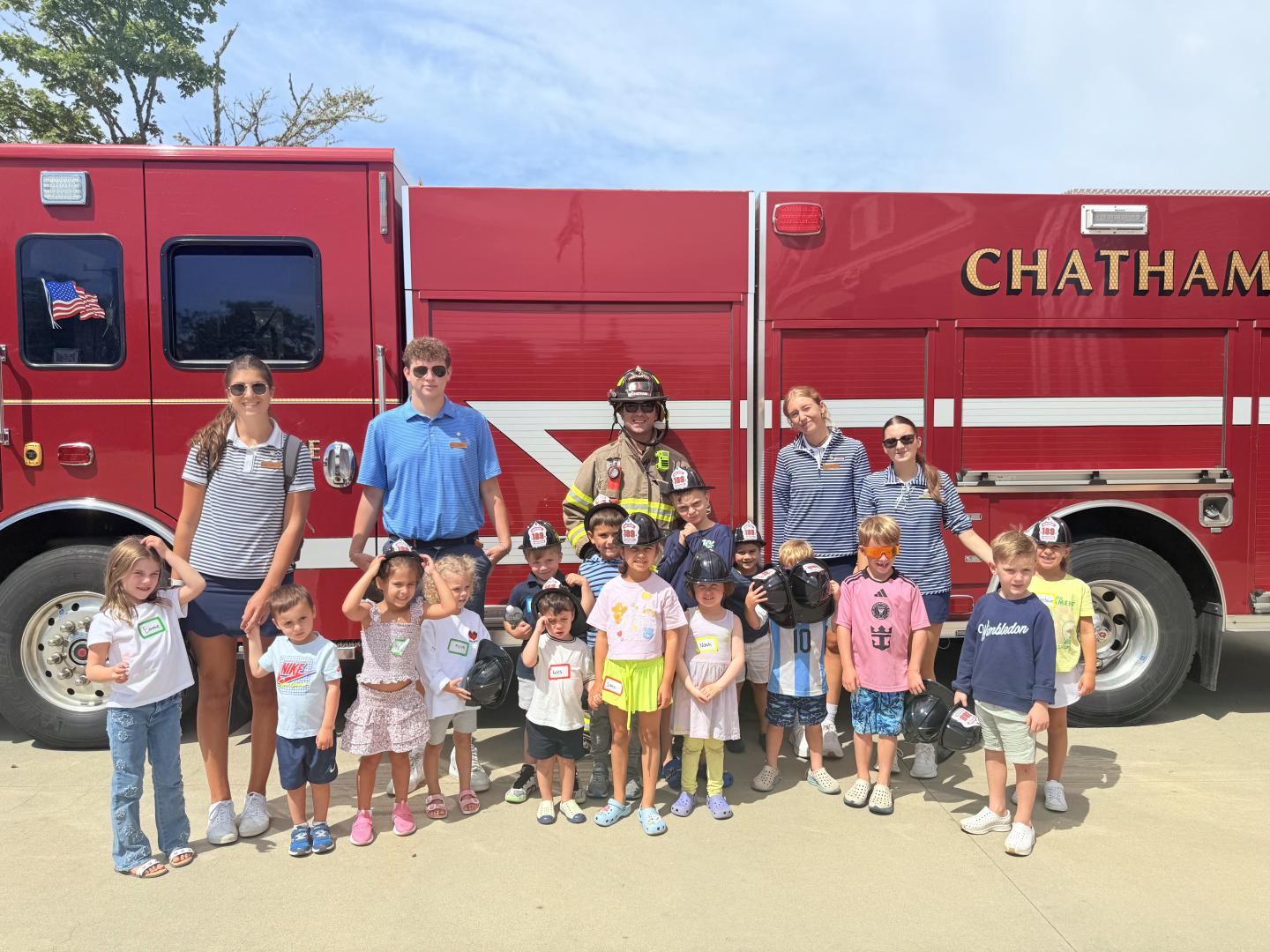 Children and adults posing in front of a red fire truck labeled "Chatham."